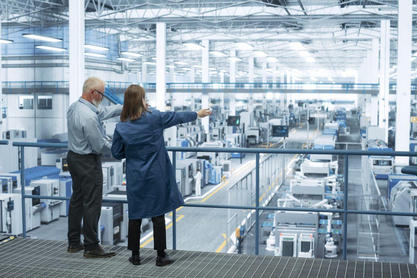 Facilities Manager talking with employee overlooking the inside of a facility.